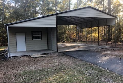 A metal garage with a carport attached to it.