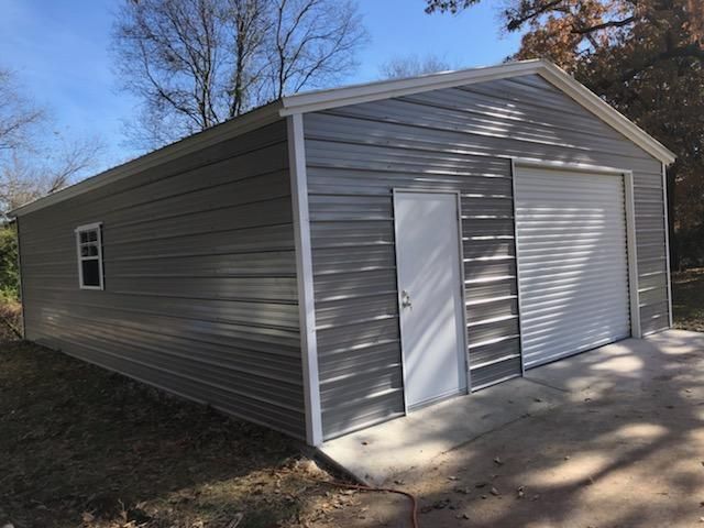 A gray metal garage with a white door and window