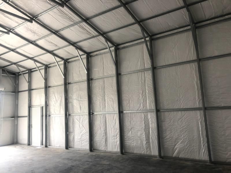 A large empty warehouse with a roof and walls covered in insulation.