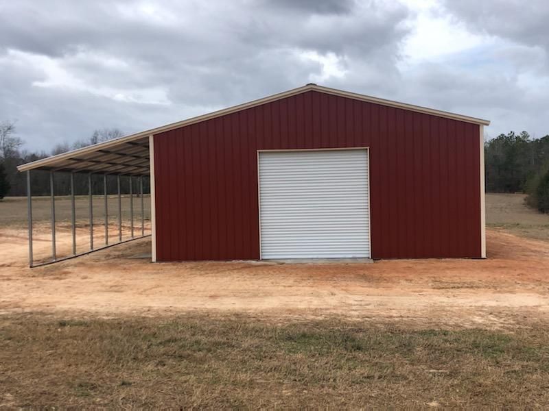 A red barn with a white door is sitting in the middle of a field.