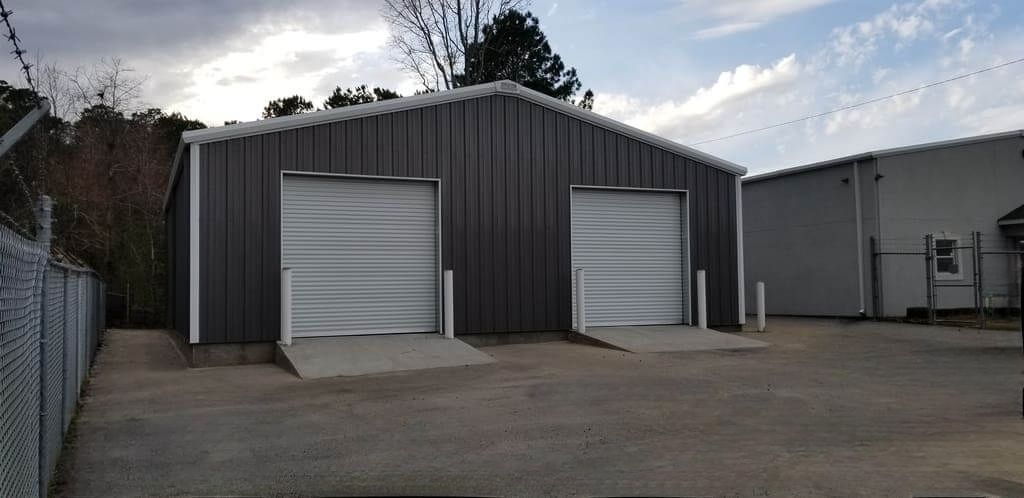 A large metal building with two garage doors in a parking lot.