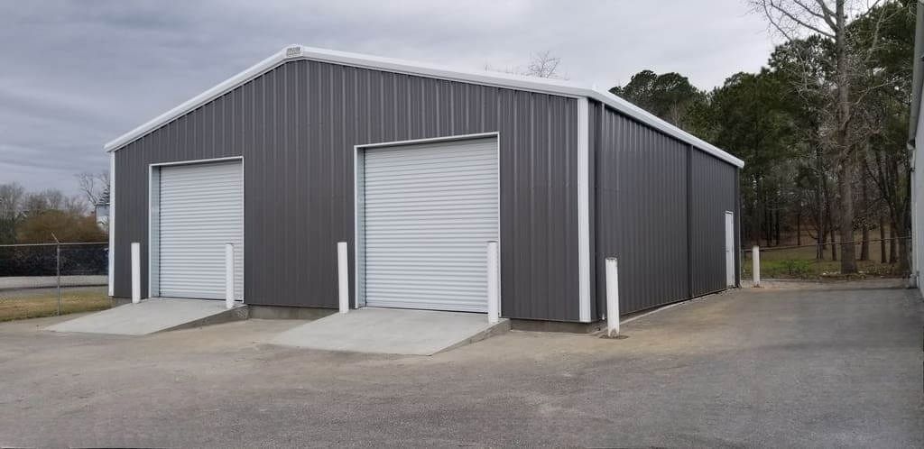 A large metal building with two garage doors and a ramp.