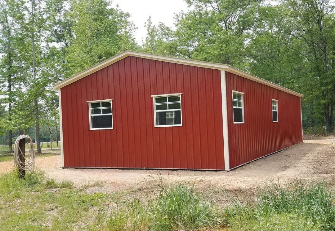 A large red barn is sitting in the middle of a field.