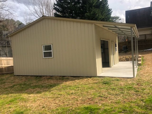 A small shed with a porch and a window in the backyard.