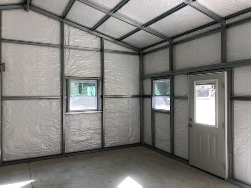An empty room with a door and two windows.