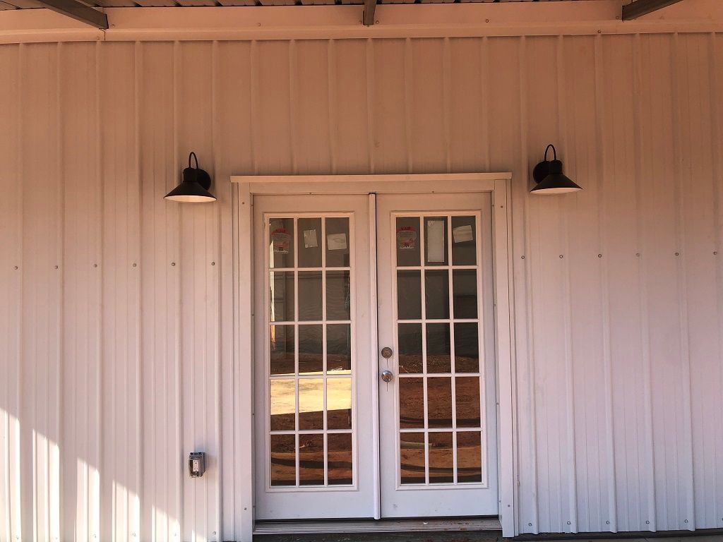 A white building with a door and two lights on the side.