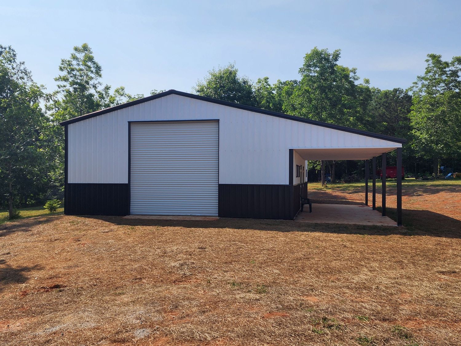 A white and black garage with a carport attached to it.
