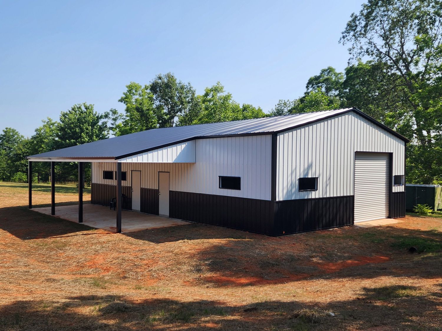 A white and black metal building with a covered porch