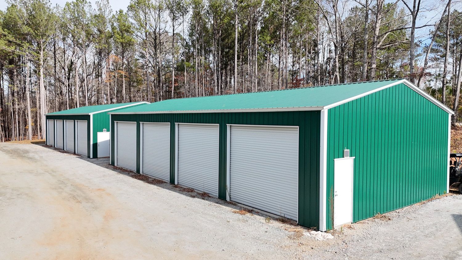 A row of green garages with white doors are lined up next to each other.