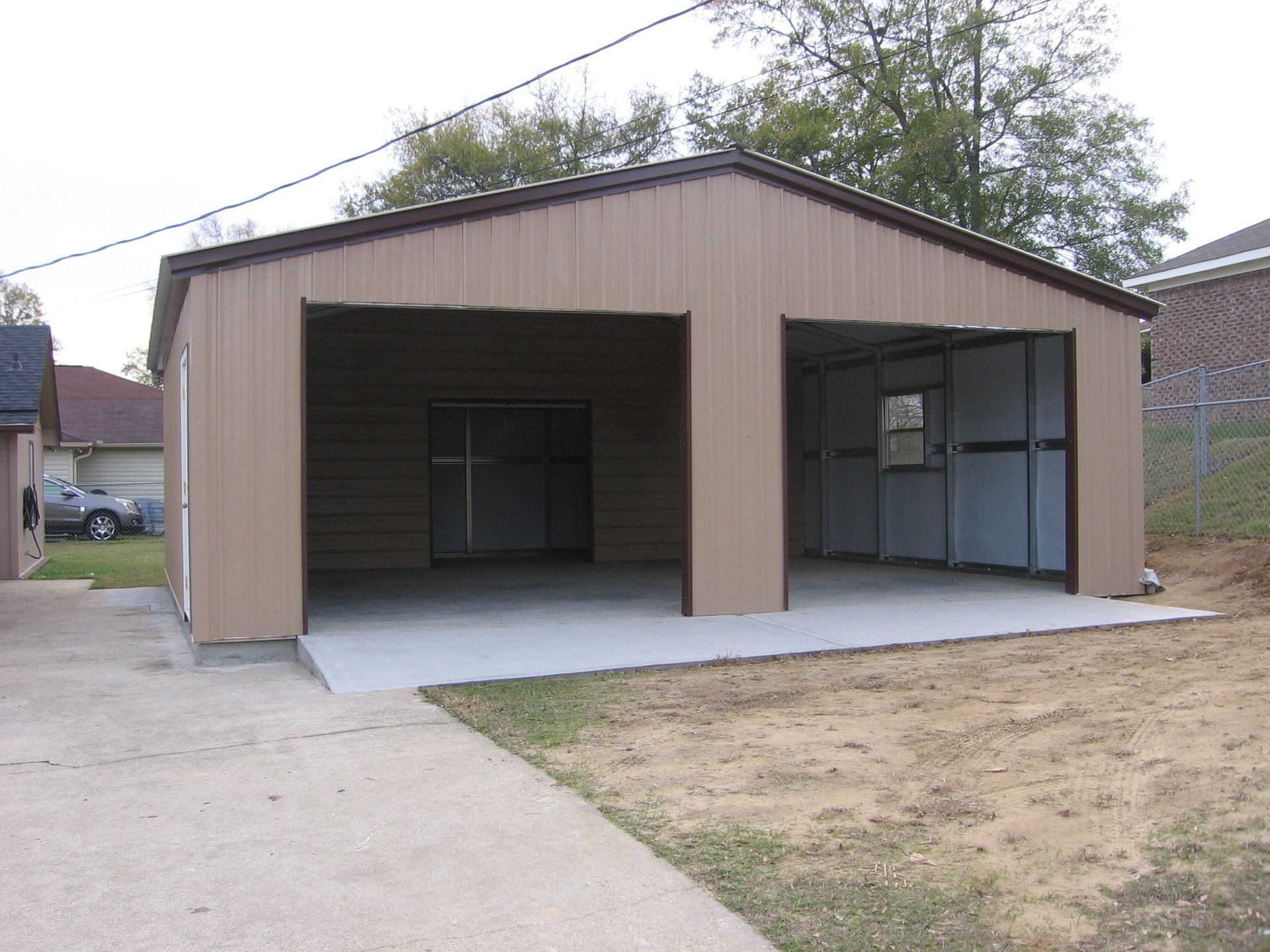 A garage with two doors open and a car parked in front of it
