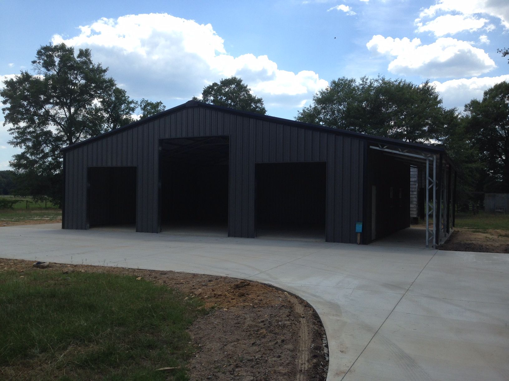 A large black building with a concrete driveway in front of it