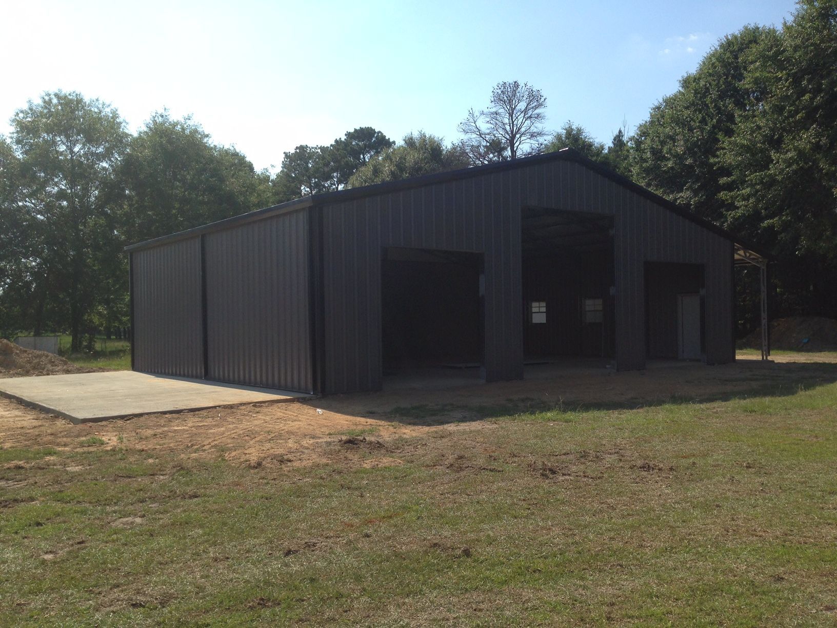 A large metal building is sitting in the middle of a grassy field.