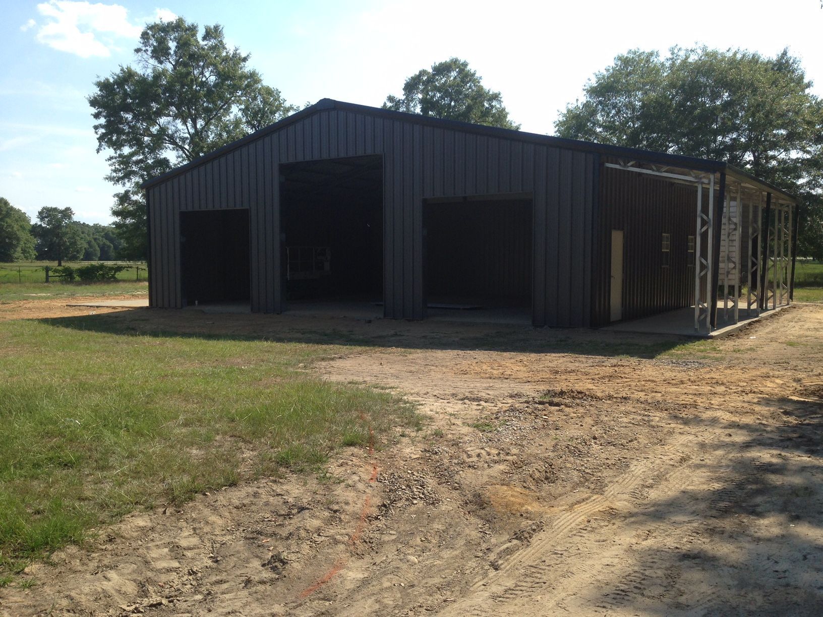 A large metal building is sitting in the middle of a grassy field