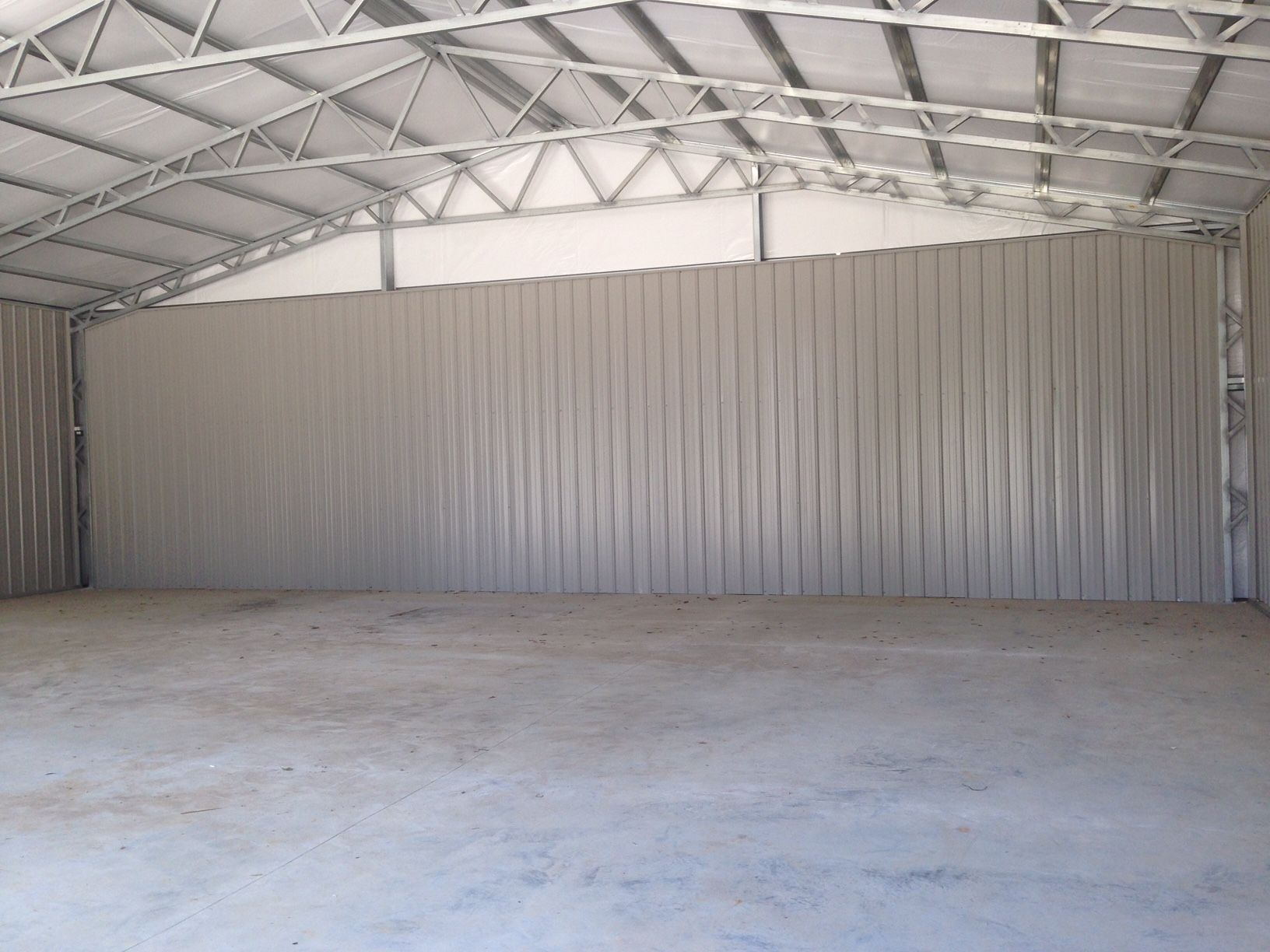 An empty warehouse with a concrete floor and a metal roof