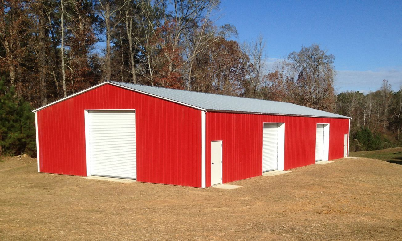 A red building with white doors is in the middle of a field