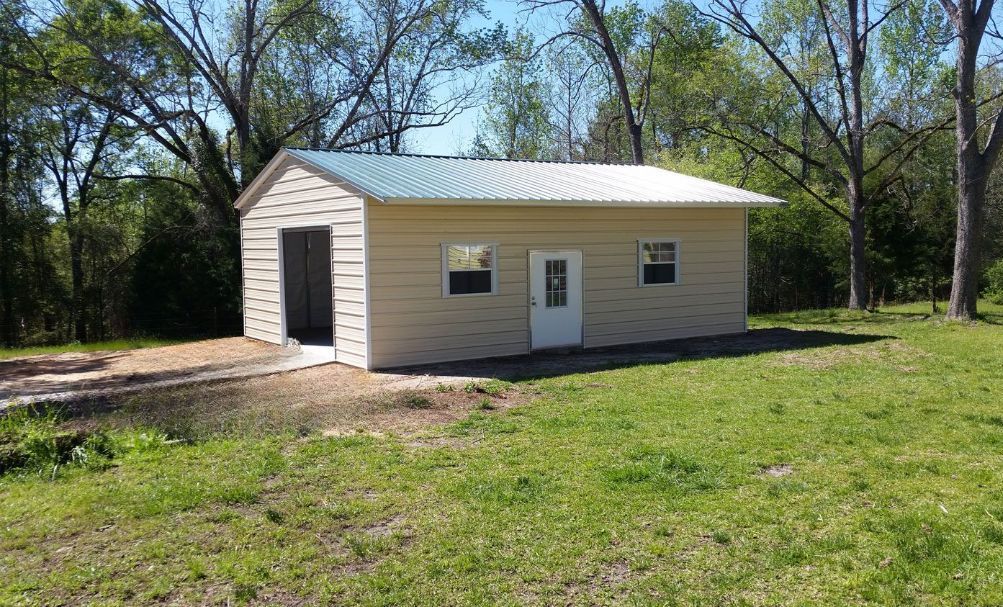 A small house is sitting in the middle of a grassy field.