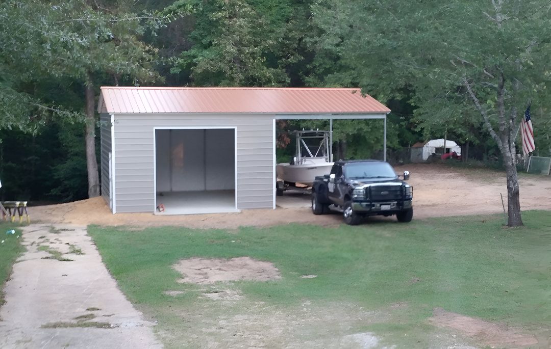 A truck is parked in front of a garage with a boat in it.
