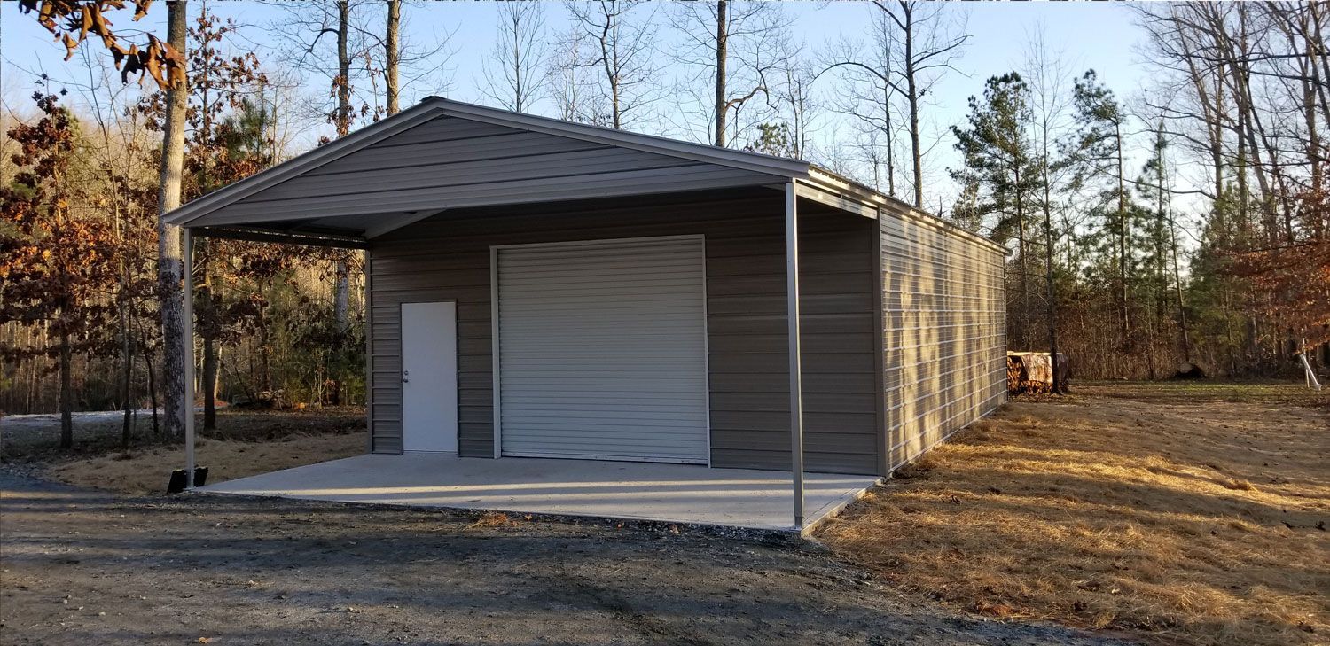 A metal garage with a white garage door is sitting in the middle of a dirt field.