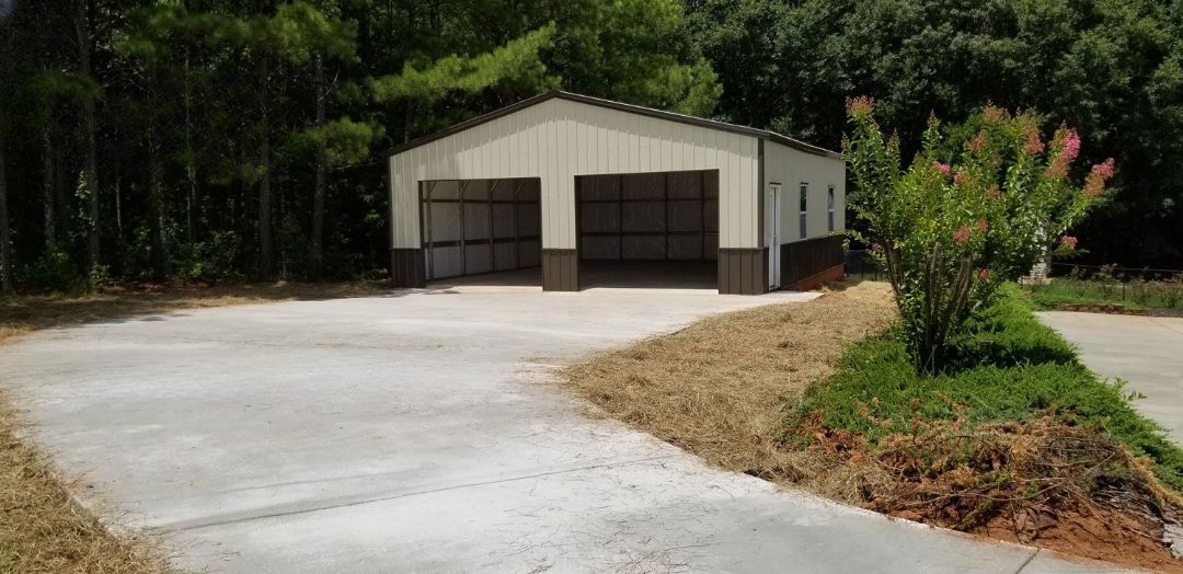 A concrete driveway leading to a garage with two garage doors.