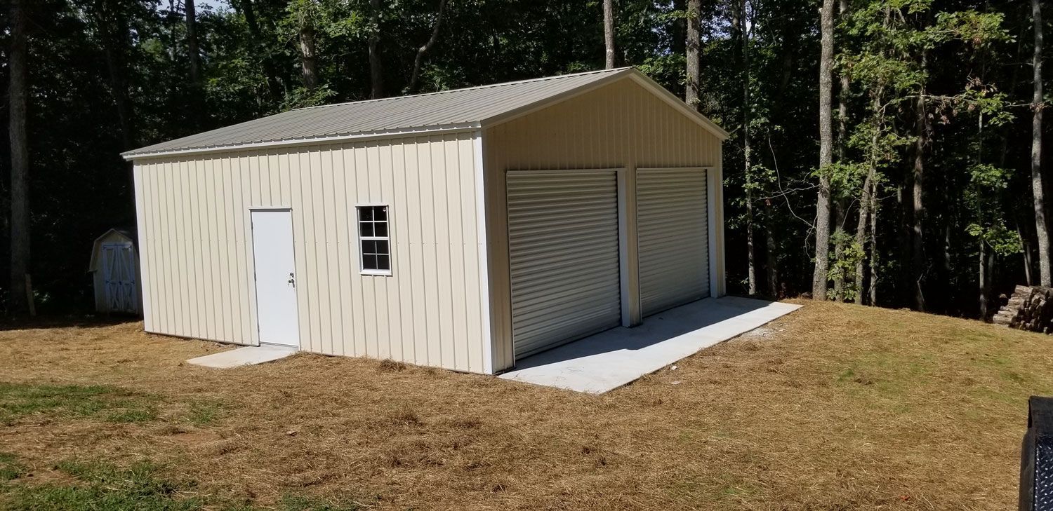 A metal garage with two garage doors is sitting on top of a grassy hill.