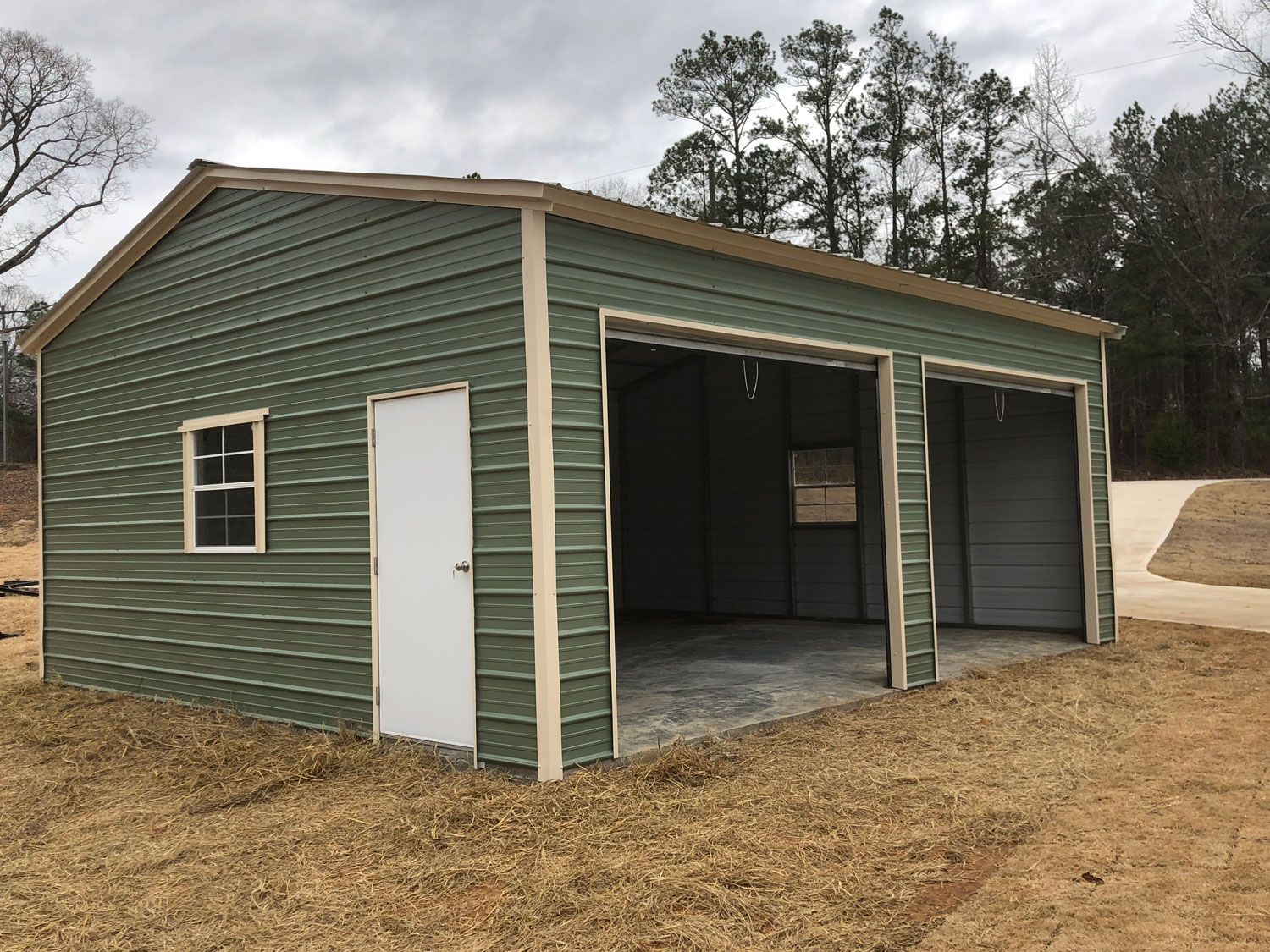 A green metal garage with two garage doors and a window.