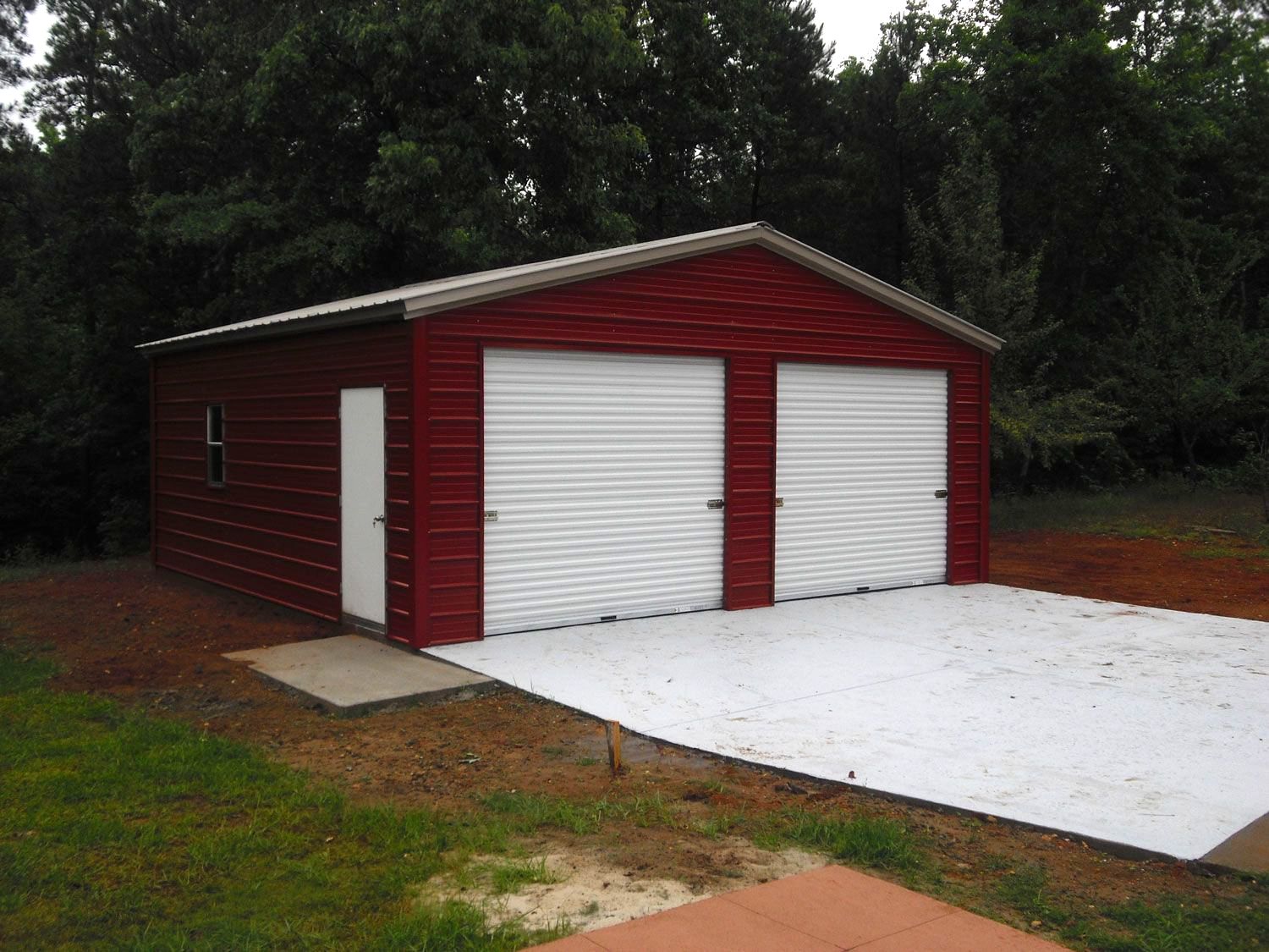 A red garage with white doors and a driveway