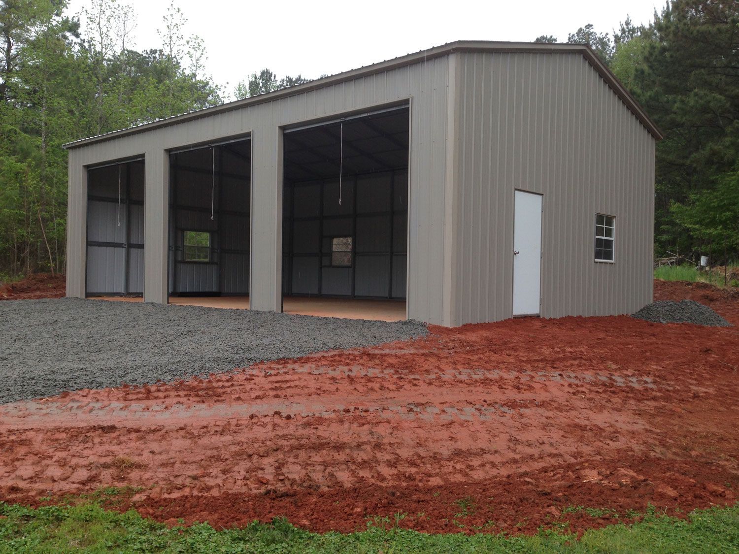 A garage with three doors is sitting in the middle of a dirt field