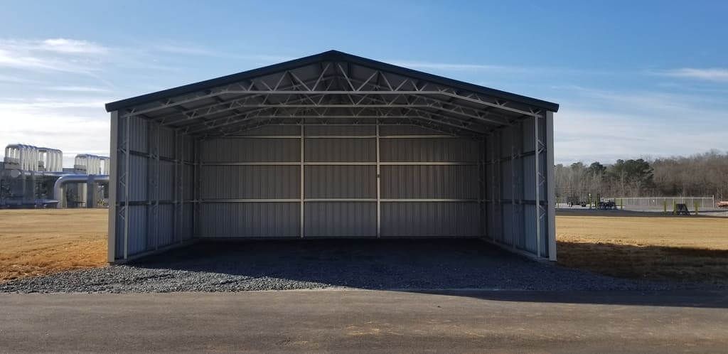 A large metal building is sitting in the middle of a field.