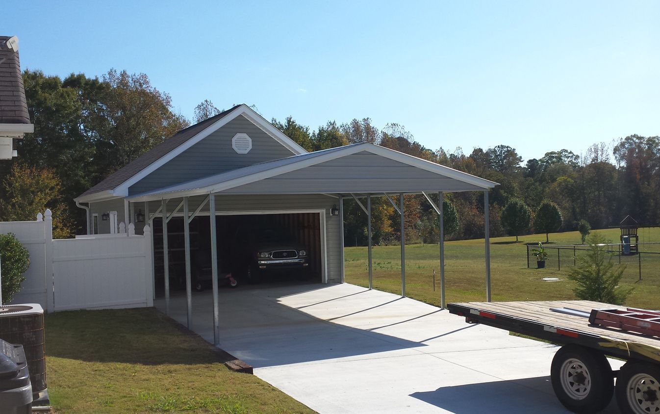 A car is parked under a carport in front of a house.