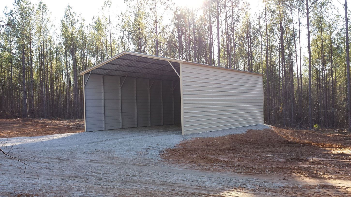 A large metal building is sitting in the middle of a forest.