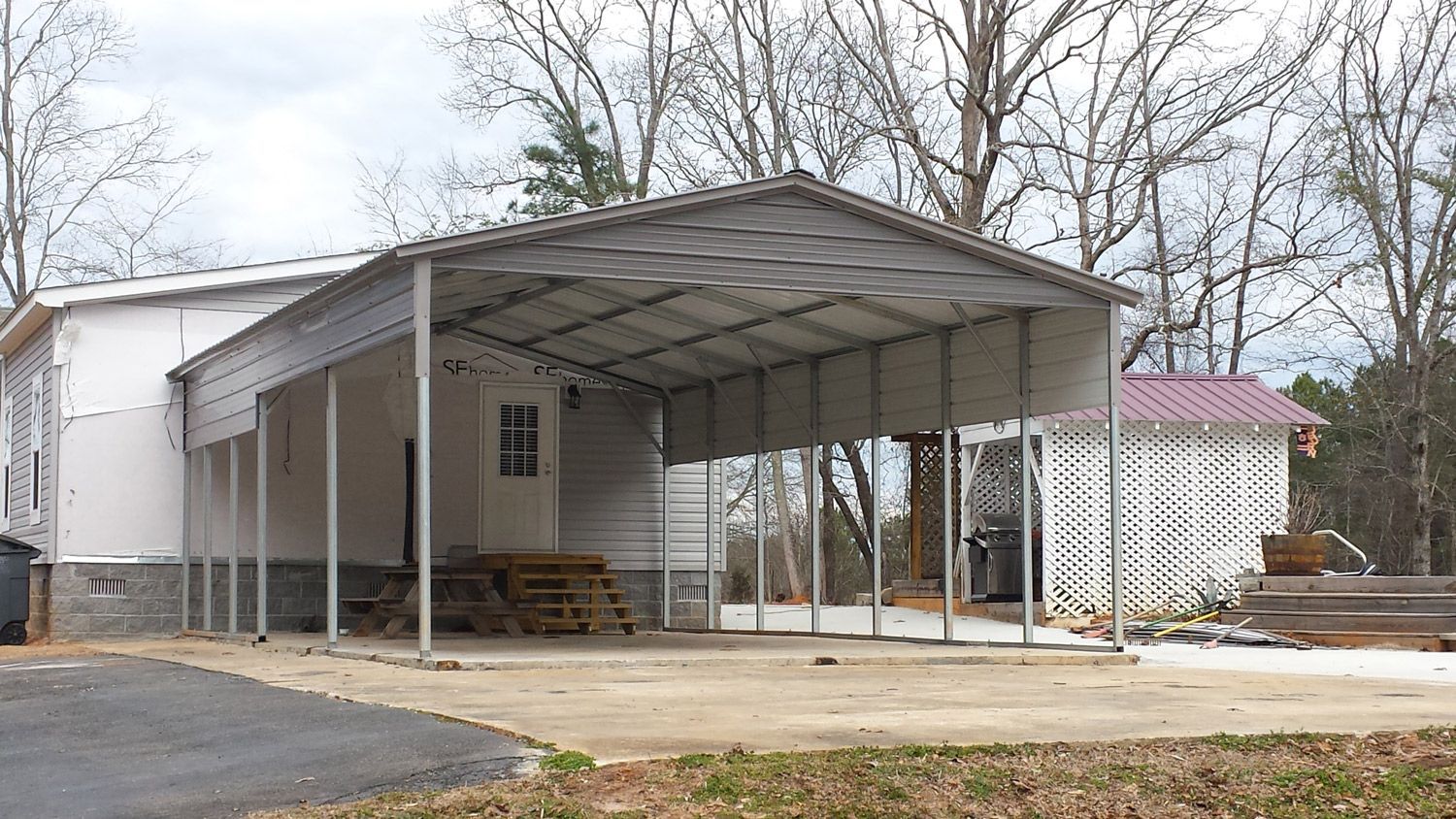 A white house with a carport attached to it.