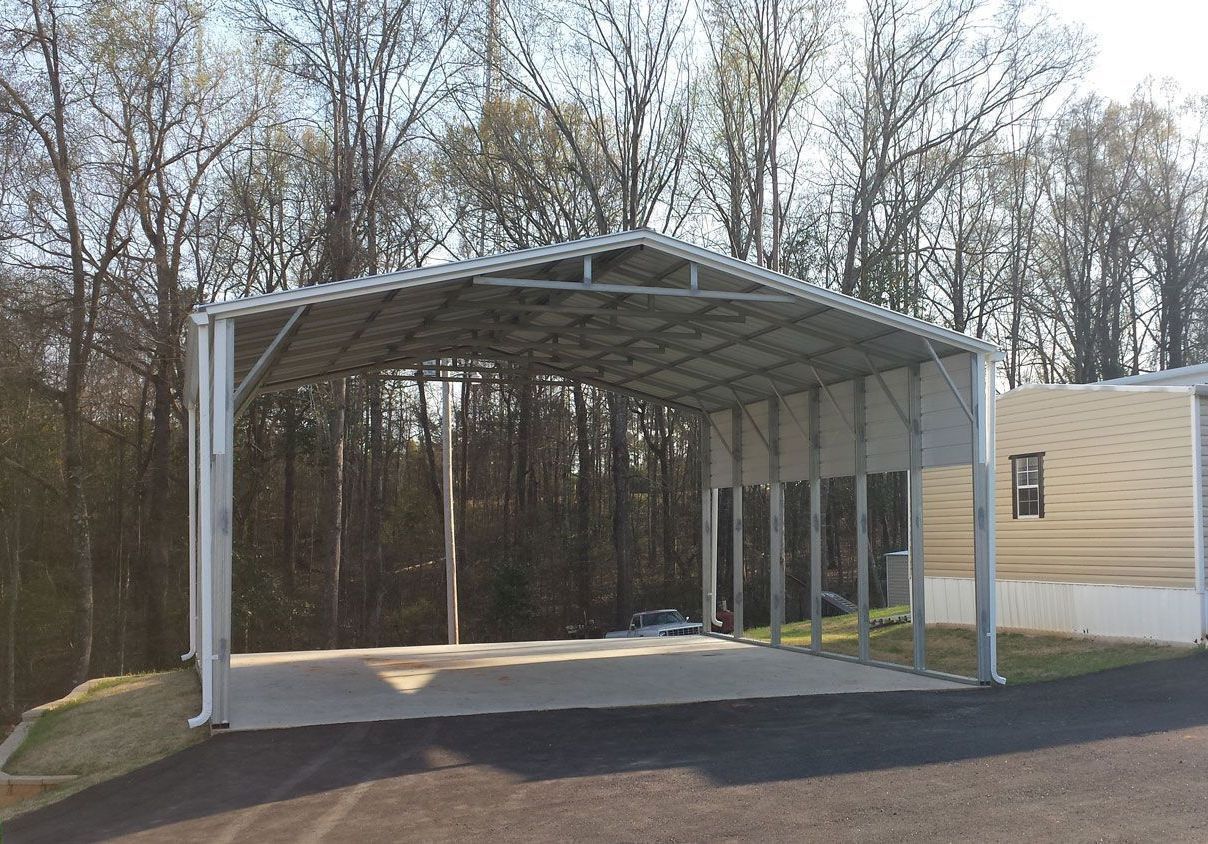 A large metal building with a driveway and trees in the background.