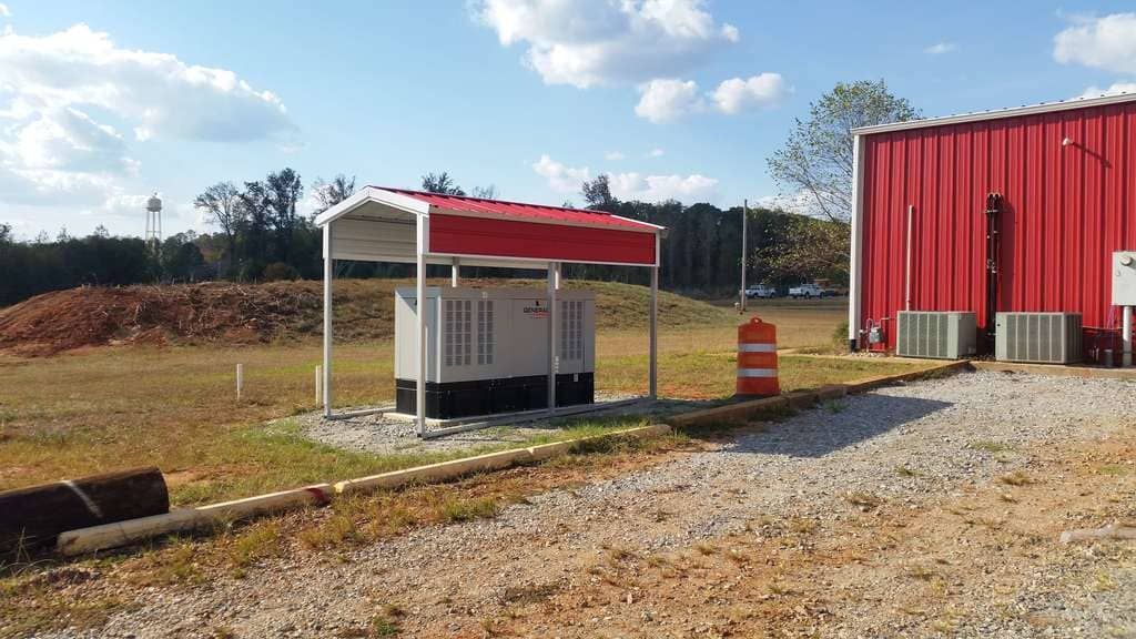 A red building with a shed in front of it in a field.