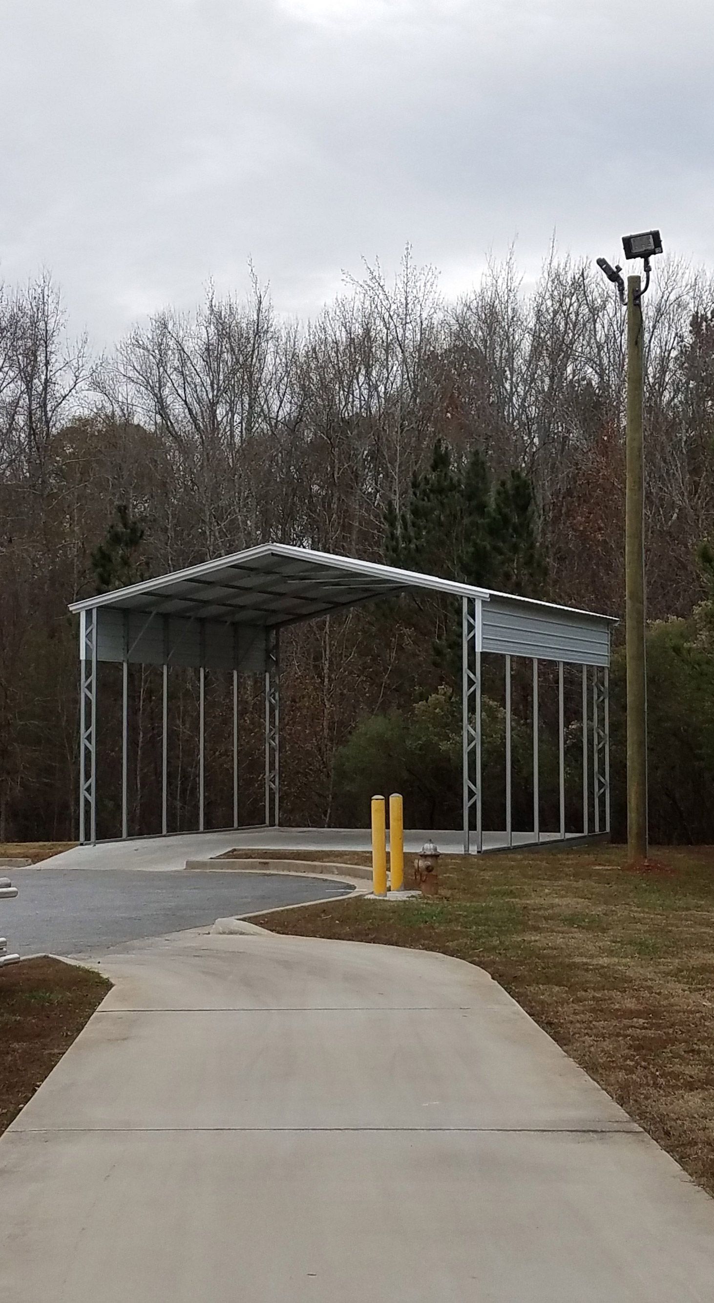 A carport is sitting on the side of a road next to a sidewalk.