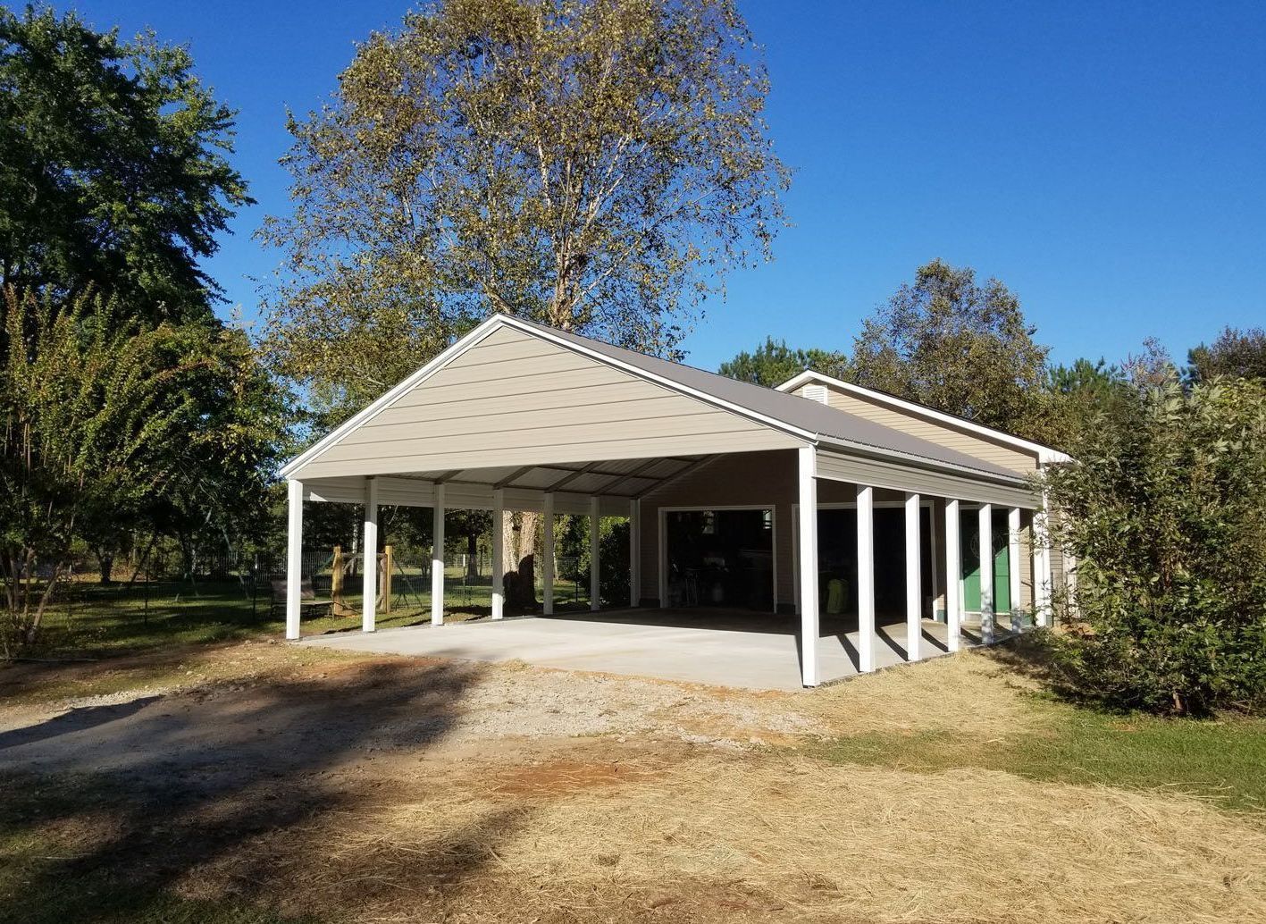 A large white garage with a porch and trees in the background.