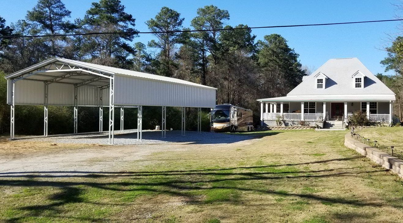 A white house with a carport in front of it.