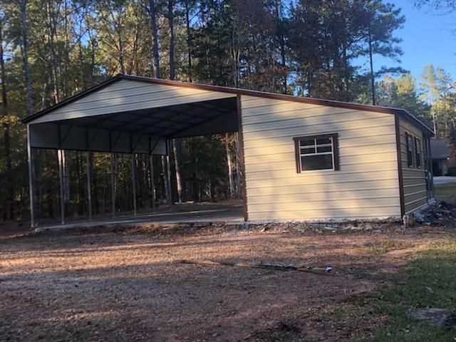 A metal garage with a window is sitting in the middle of a dirt field.
