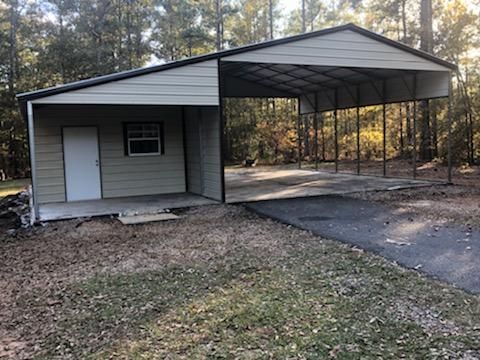 A metal garage with a carport attached to it.