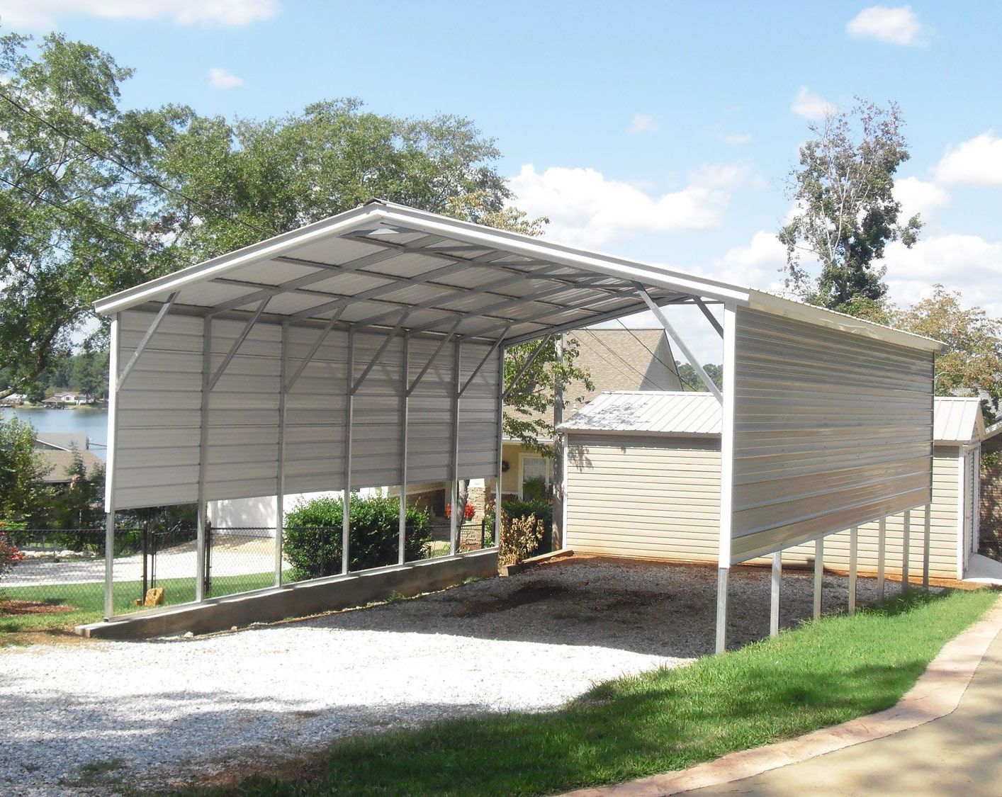 A carport is sitting in the grass in front of a house