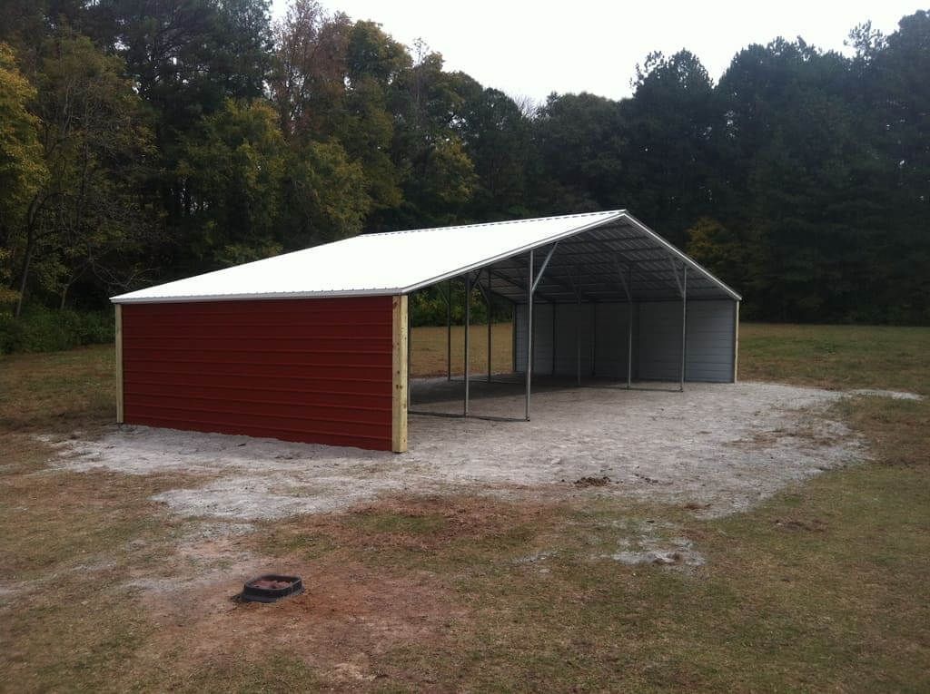 A red barn with a white roof is in the middle of a field.