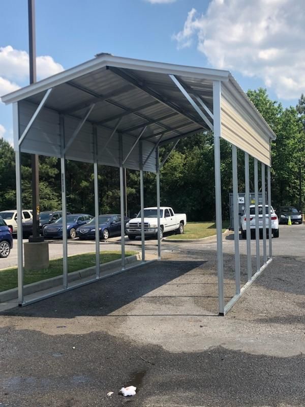 A carport in a parking lot with cars parked underneath it