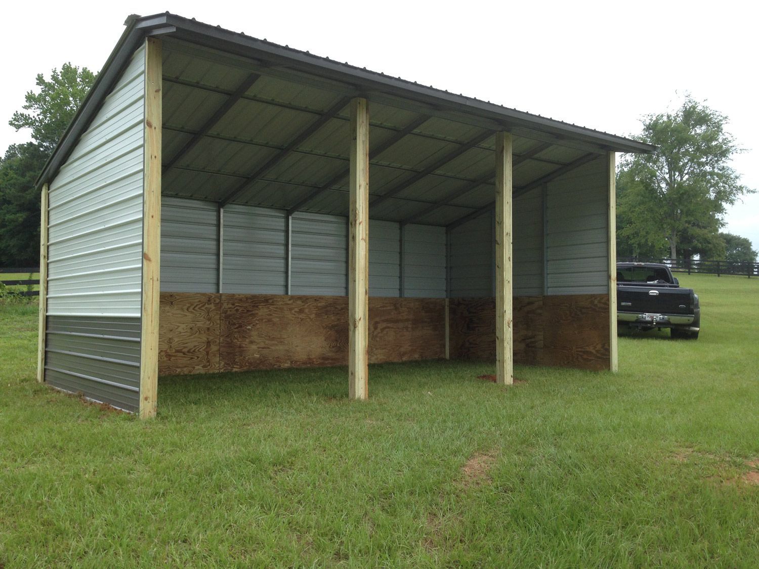 A shed is sitting in the middle of a grassy field.