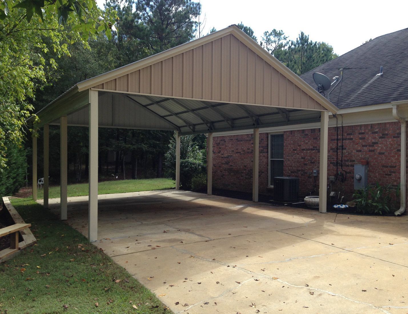 A carport is attached to the side of a brick house.