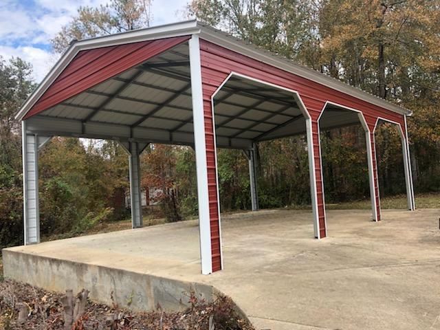 A red and white carport is sitting on top of a concrete driveway.
