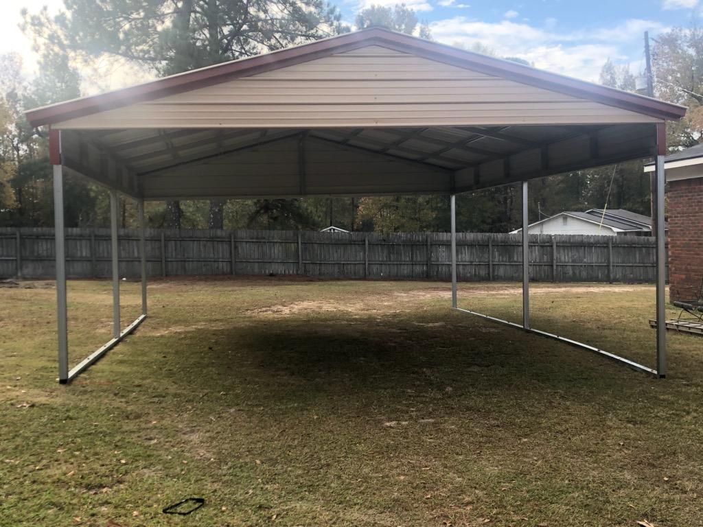 A carport is sitting in the middle of a grassy field.