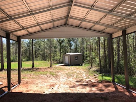 A metal garage with a shed in the middle of a field.