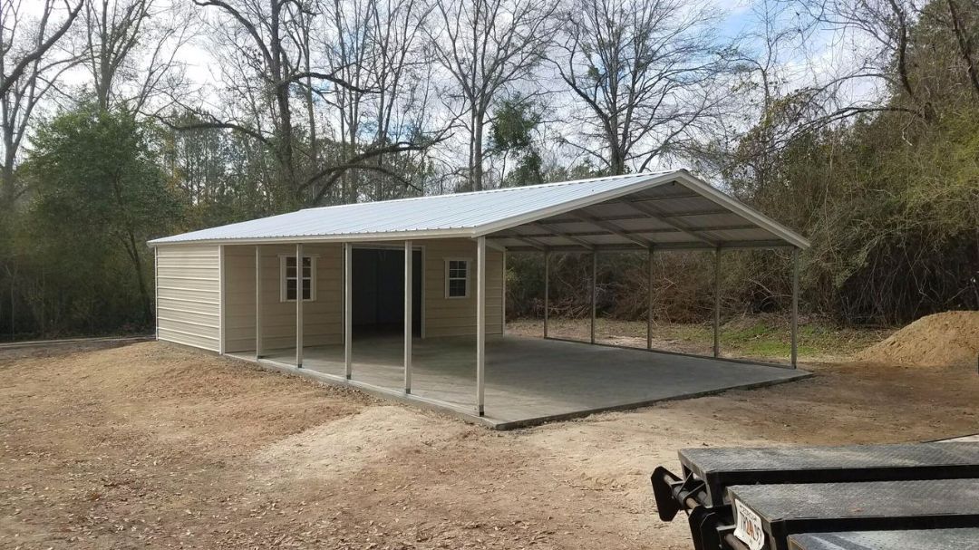 A carport is sitting in the middle of a dirt field next to a trailer.
