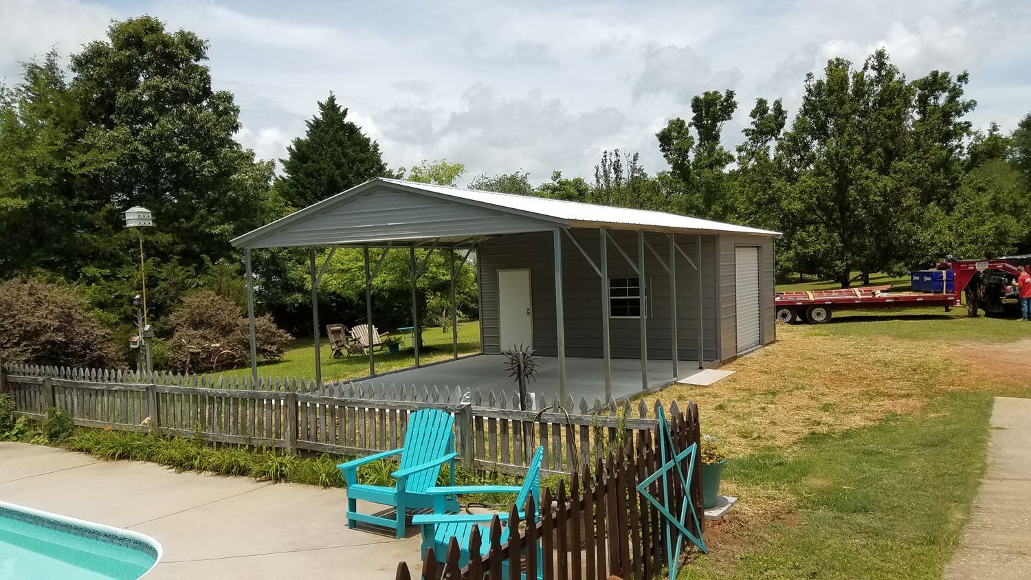 A carport is sitting next to a pool in a backyard.