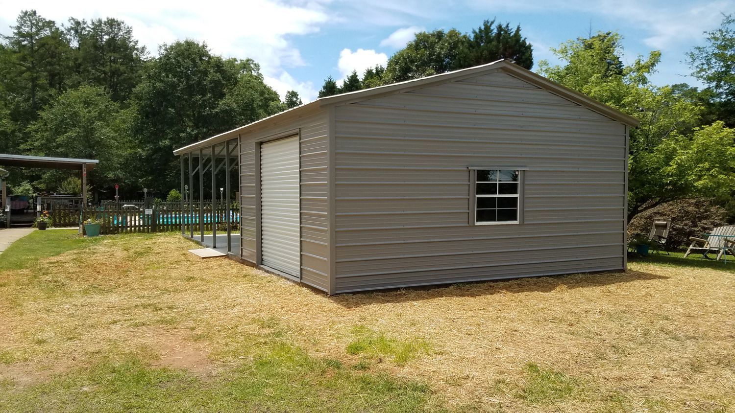 A small shed with a garage door and a window is sitting in the middle of a grassy field.