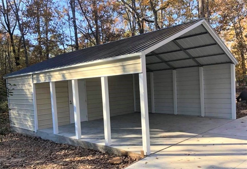 A white garage with a black roof is sitting next to a concrete driveway.